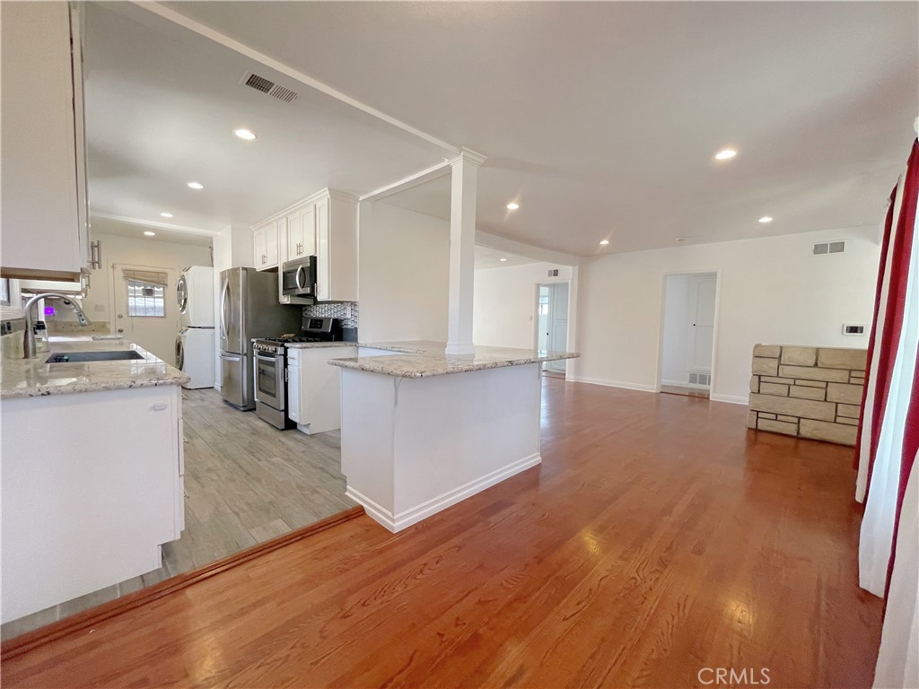 15100 Dunton Drive Whittier, CA 90604 - Photo 9 of 17 a kitchen with stainless steel appliances granite countertop a stove top oven a sink a refrigerator white cabinets and wooden floor