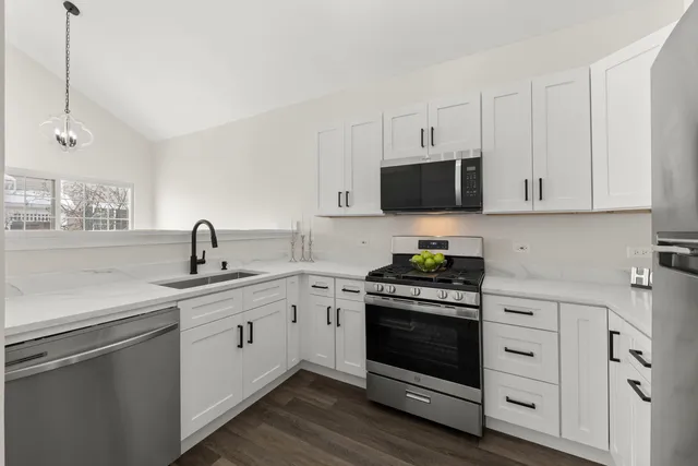 a kitchen with white cabinets and appliances
