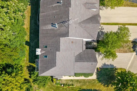 an aerial view of residential house with outdoor space and trees all around