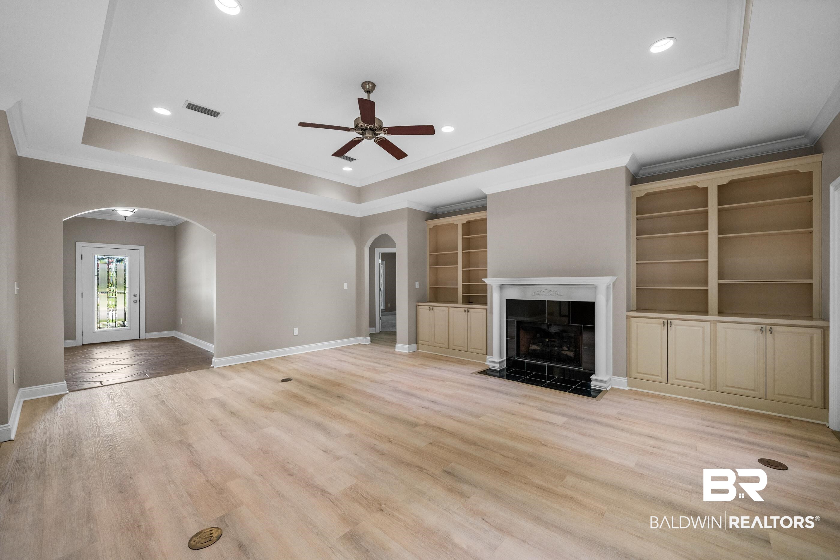 303 Savannah Circle Foley, AL 36535 - Photo 6 of 34 Spacious living area featuring light wood-finish flooring, a tray ceiling with recessed lighting, and a ceiling fan