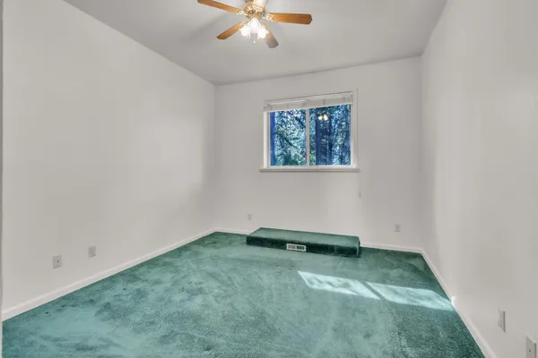 an empty room with a ceiling fan and window