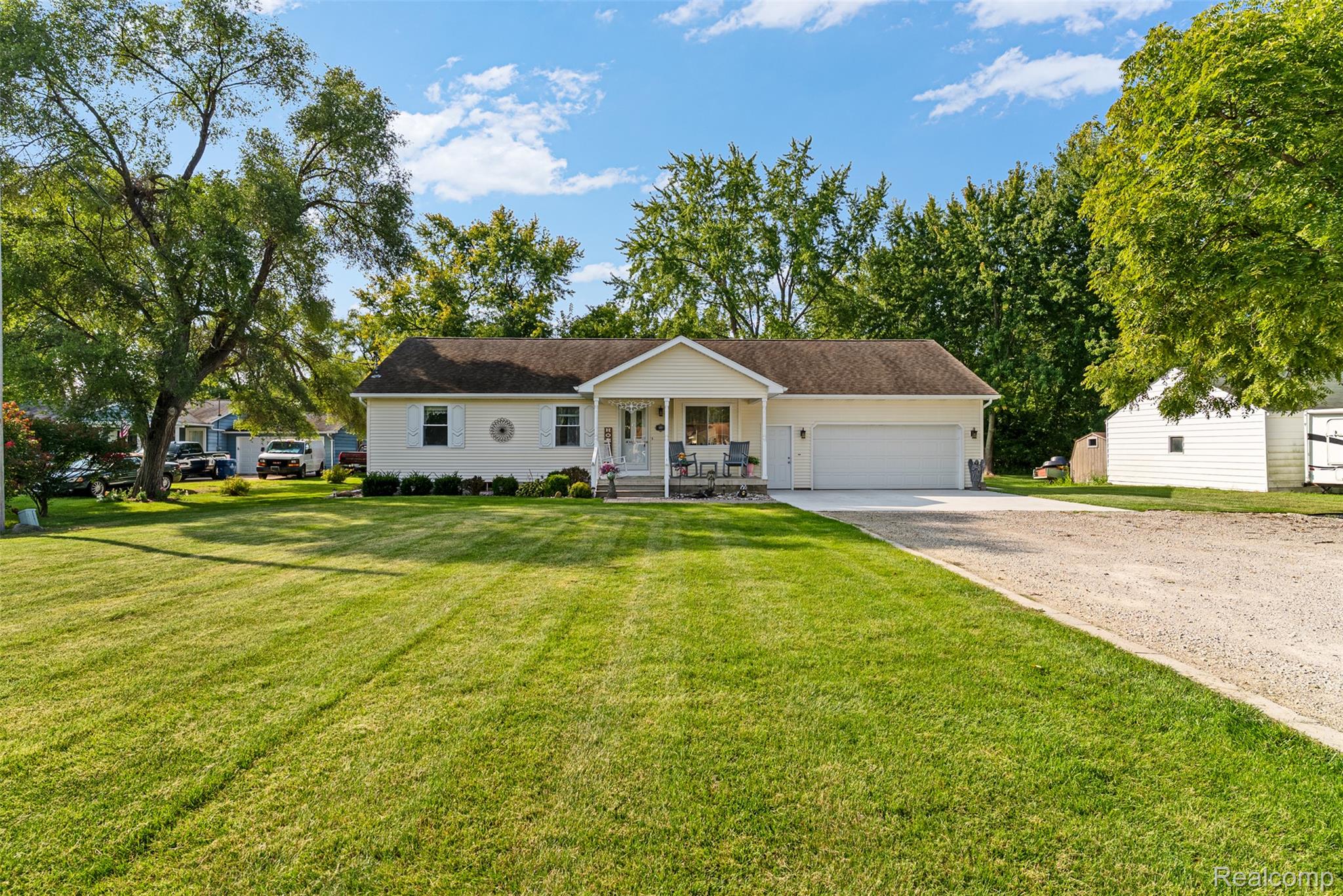 Ranch-style house with a porch, driveway, a front yard, and an attached garage