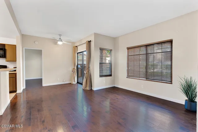 a view of an empty room with window and wooden floor