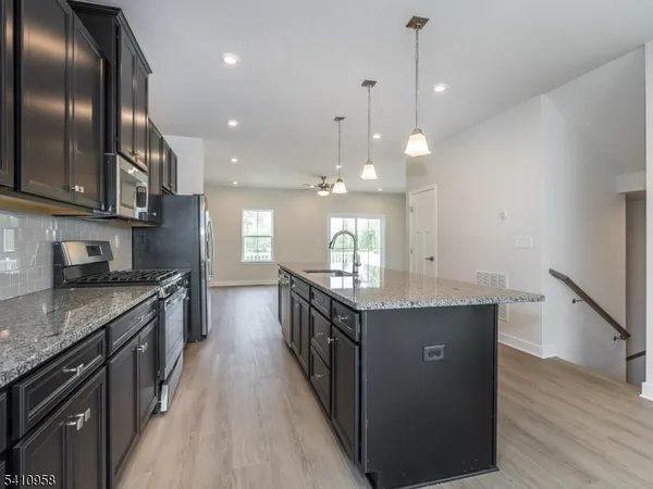 a kitchen with granite countertop a sink a counter top space stove and cabinets