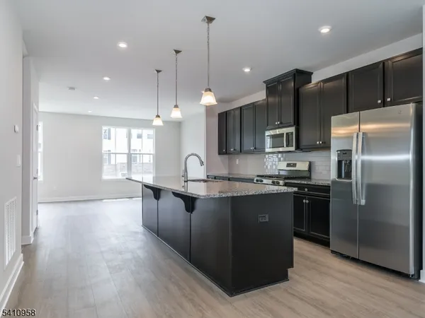 a kitchen with stainless steel appliances granite countertop a refrigerator a sink a stove and wooden floors