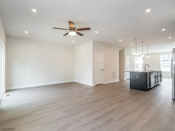 a view of an empty room with wooden floor and a ceiling fan