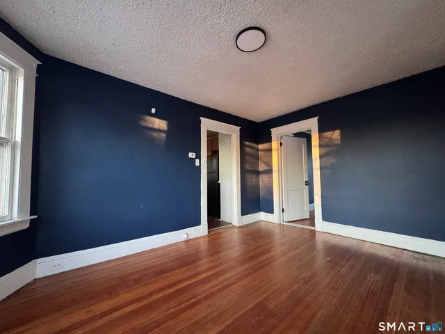 a view of an empty room with wooden floor and a window