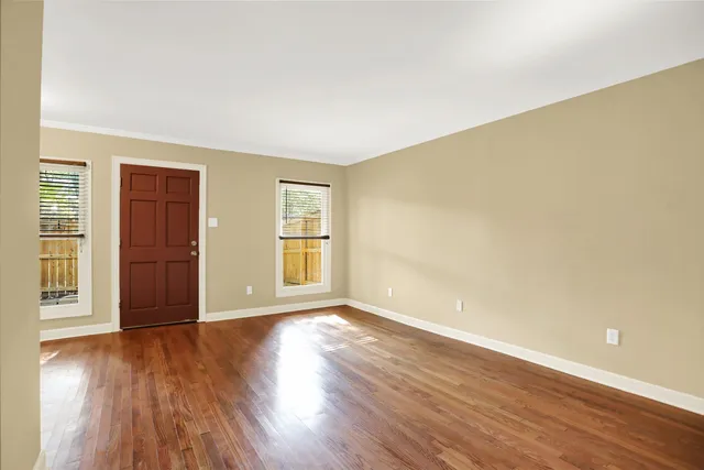 a view of an empty room with wooden floor and a window