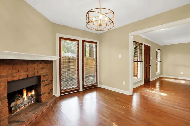 an empty room with wooden floor fireplace and windows