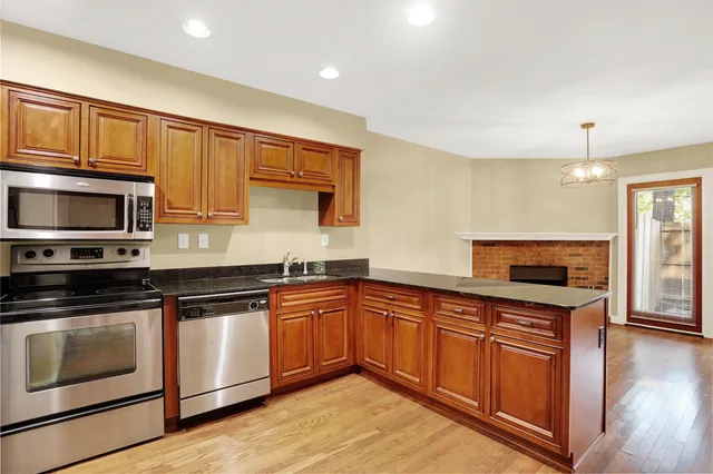a kitchen with stainless steel appliances granite countertop wooden cabinets a stove a sink and a microwave