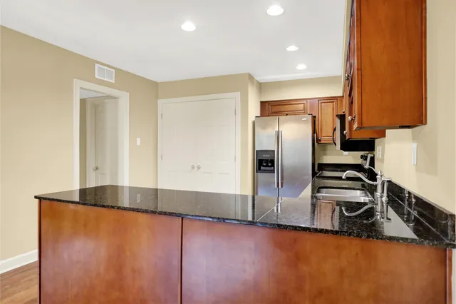 a kitchen with stainless steel appliances granite countertop a refrigerator a stove and a sink with wooden floor