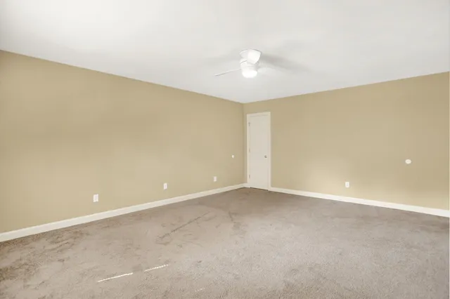 a view of an empty room with a chandelier fan