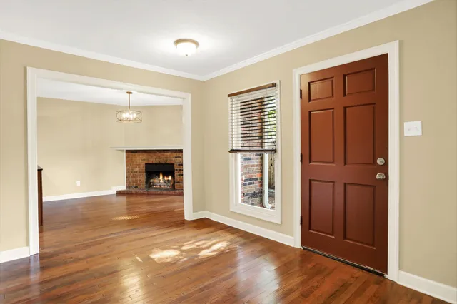 an empty room with wooden floor fireplace and windows