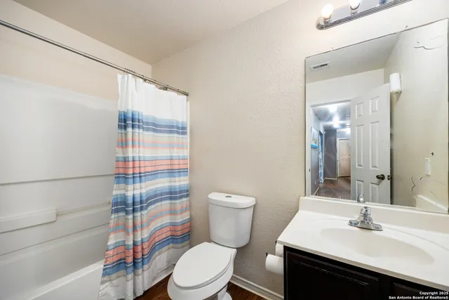 a bathroom with a sink a toilet a mirror and shower