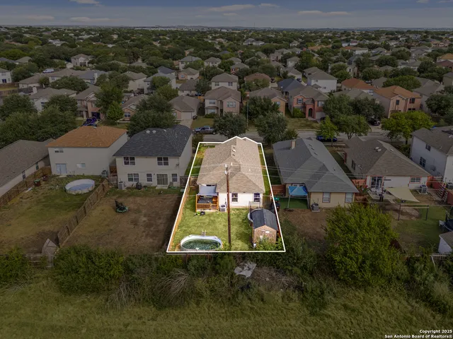 an aerial view of residential houses with outdoor space and trees
