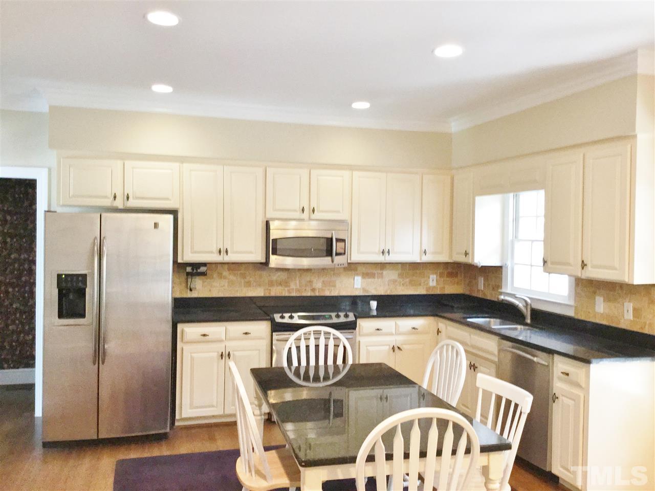11604 Chipaway Court Raleigh, NC 27614 - Photo 3 of 25 a kitchen with granite countertop a refrigerator a sink a stove a dining table and chairs