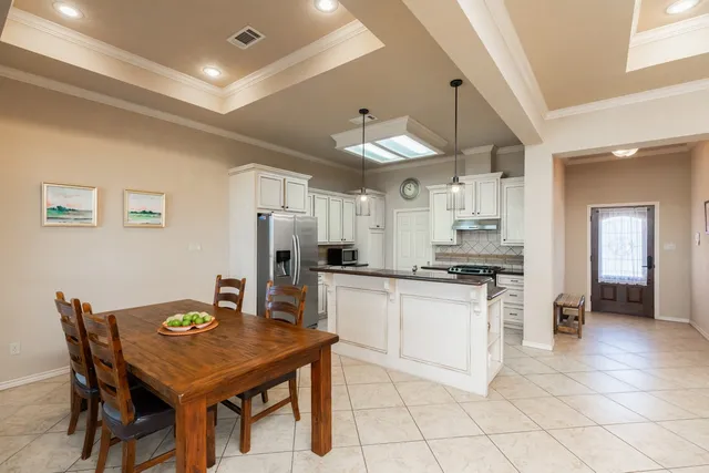 a kitchen with stainless steel appliances kitchen island granite countertop a table chairs and a refrigerator