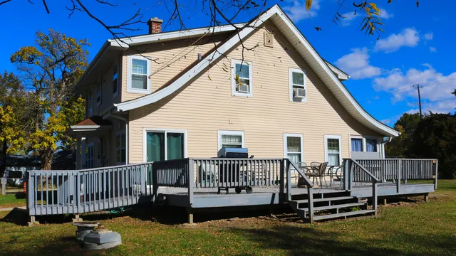a view of a house with a wooden deck and furniture