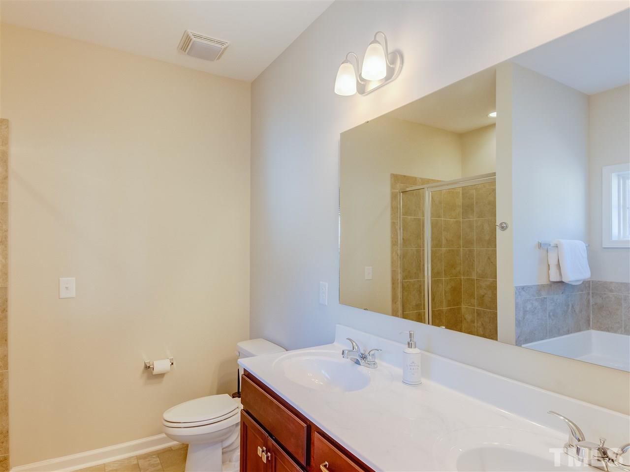30 Mariners Point Way Garner, NC 27529 - Photo 14 of 25 Luxury Master Bath has tiled double shower, double marble sink counter, wood cabinets/vanity, garden with transom window above.