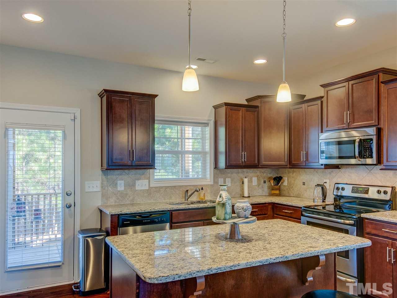 30 Mariners Point Way Garner, NC 27529 - Photo 8 of 25 Fantastic kitchen with center island. Quality wood cabinetry, granite counters, tile back splash, stainless steel appliances, recessed ceiling lighting, pendant lighting over island and hardwood floor. Glass door to screened porch.
