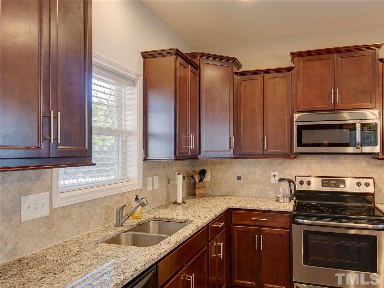 30 Mariners Point Way Garner, NC 27529 - Photo 10 of 25 Fantastic kitchen with center island and window over sink. Quality wood cabinetry, granite counters, tile back splash, stainless steel appliances, recessed ceiling lighting, pendant lighting over island and hardwood floor. Glass