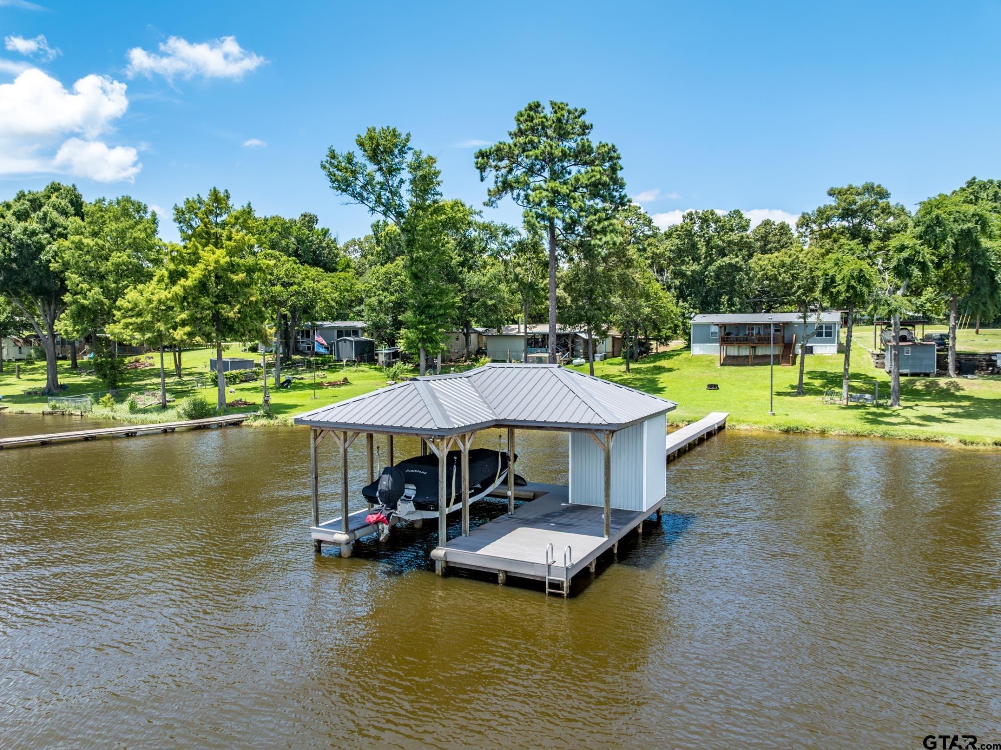 21516 Water Ridge Road Chandler, TX 75758 - Photo 44 of 48 a view of a lake with a table and chairs under an umbrella