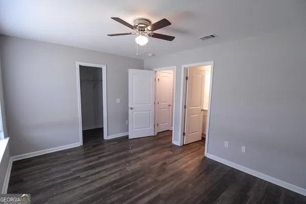 an empty room with wooden floor and ceiling fan