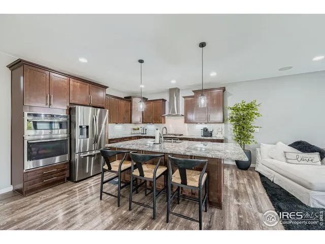 a kitchen with stainless steel appliances a dining table chairs and refrigerator