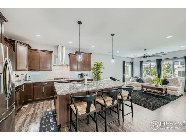 a kitchen with stainless steel appliances granite countertop a table chairs stove and refrigerator