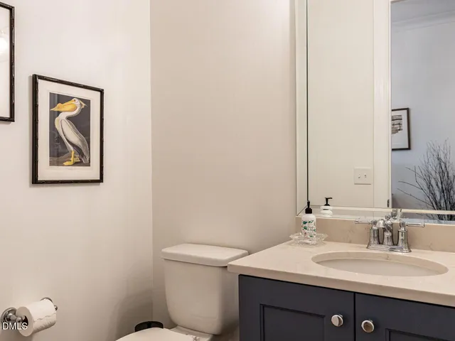 a bathroom with a toilet a sink a mirror a window and vanity