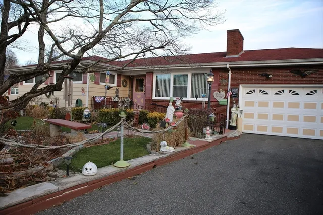 a front view of a house with a garden and trees