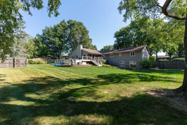 a view of a house with a big yard and potted plants and large trees
