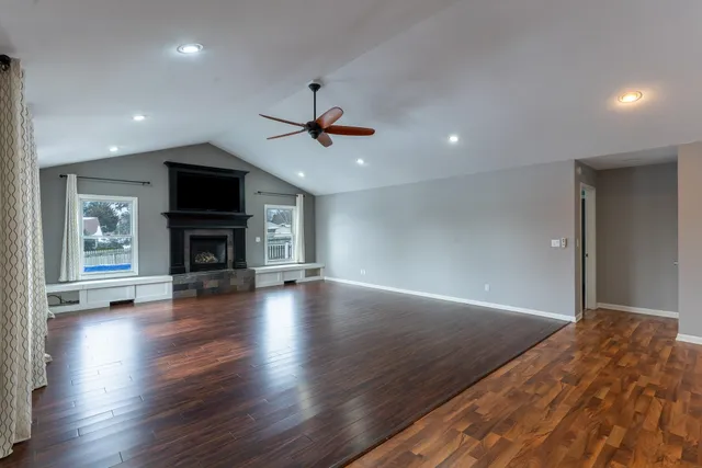 an empty room with wooden floor fireplace and a window