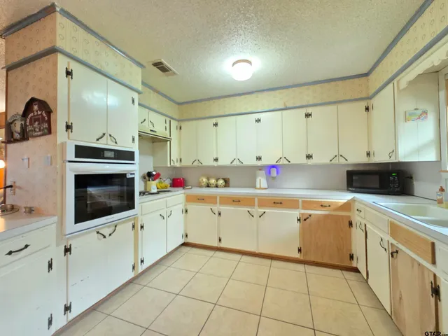 a kitchen with white cabinets a sink dishwasher and a stove with wooden floor