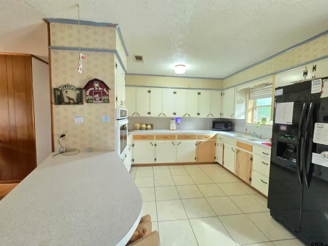 a large white kitchen with a stove a refrigerator and a sink