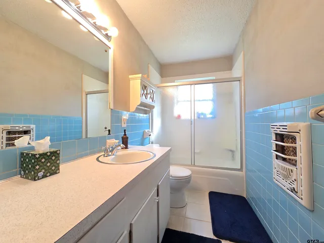 a bathroom with a granite countertop sink a toilet and shower