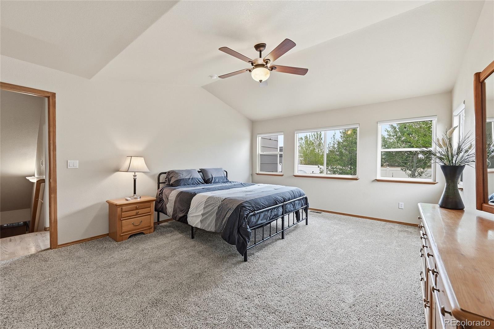 9288 Rockingham Drive Peyton, CO 80831 - Photo 16 of 49 a spacious bedroom with a large bed and a chandelier