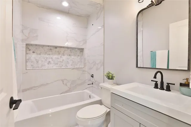 a bathroom with a bathtub shower sink vanity mirror and toilet