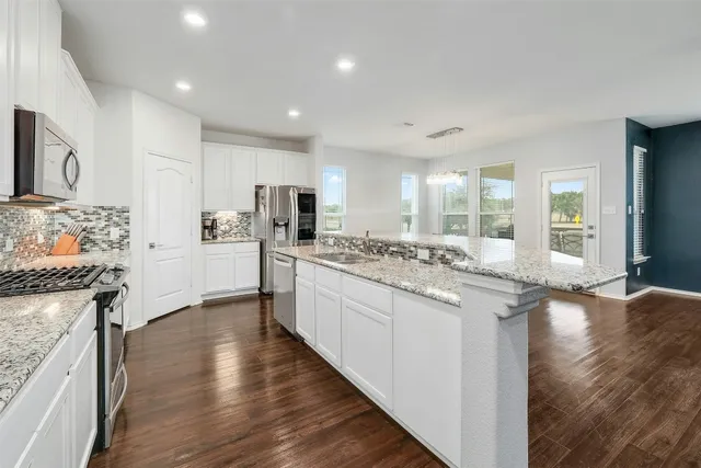 a kitchen with stainless steel appliances granite countertop a refrigerator a stove and a wooden floors