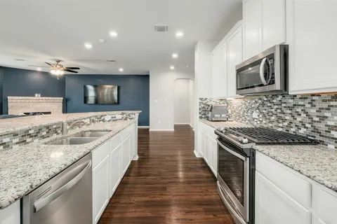 a kitchen with granite countertop a stove sink and refrigerator