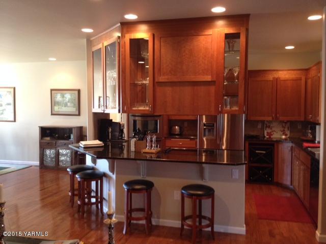 5305 Lombard Loop Road Zillah, WA 98953 - Photo 14 of 27 a open kitchen with stainless steel appliances granite countertop a stove a refrigerator a kitchen island a dining table and chairs with wooden floor