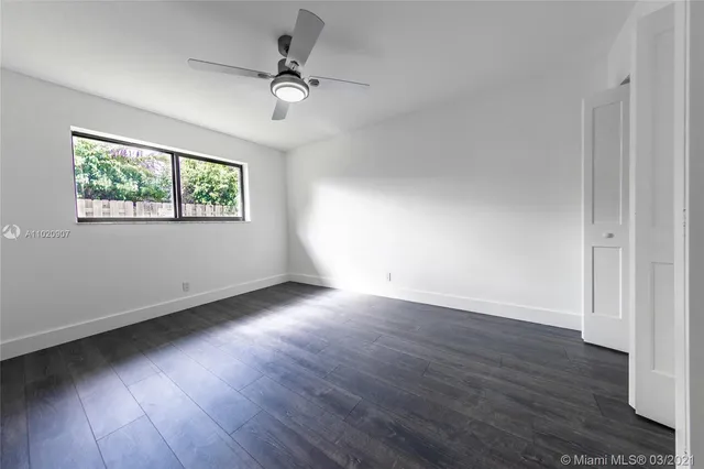 an empty room with wooden floor chandelier fan and windows