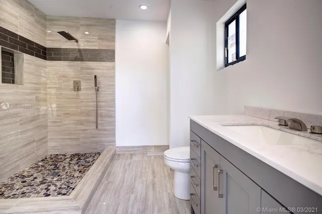 a bathroom with a granite countertop sink toilet and shower