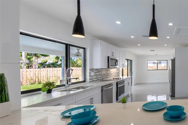 a kitchen with stainless steel appliances granite countertop a sink a stove and a wooden floors
