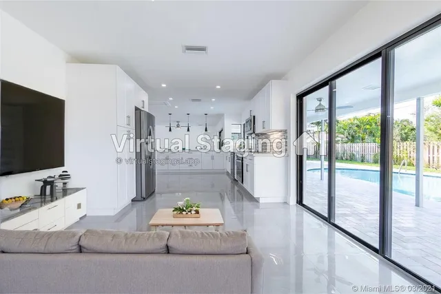 a room with stainless steel appliances kitchen island granite countertop a refrigerator and a sink