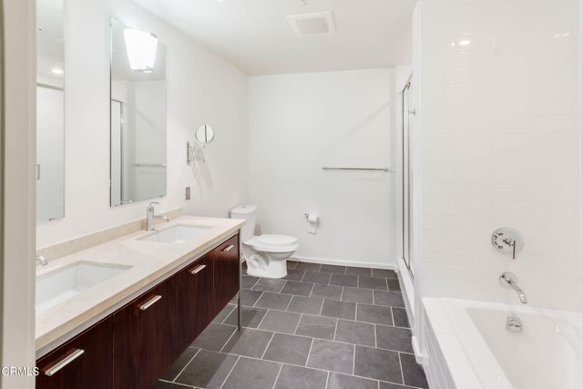 a bathroom with a granite countertop sink a toilet and shower