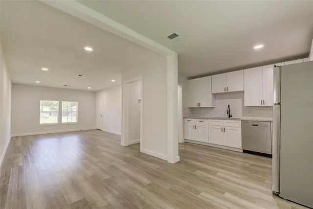 a kitchen with a refrigerator and white cabinets