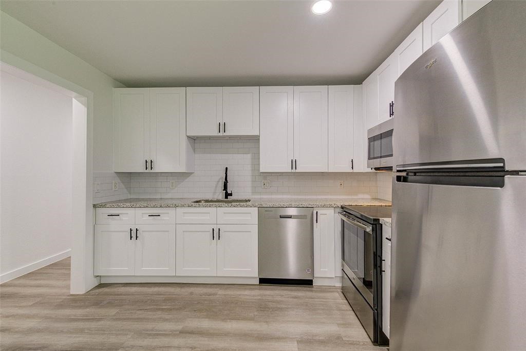 4218 Friar Point Road Houston, TX 77047 - Photo 14 of 26 a kitchen with stainless steel appliances granite countertop a refrigerator a sink and white cabinets