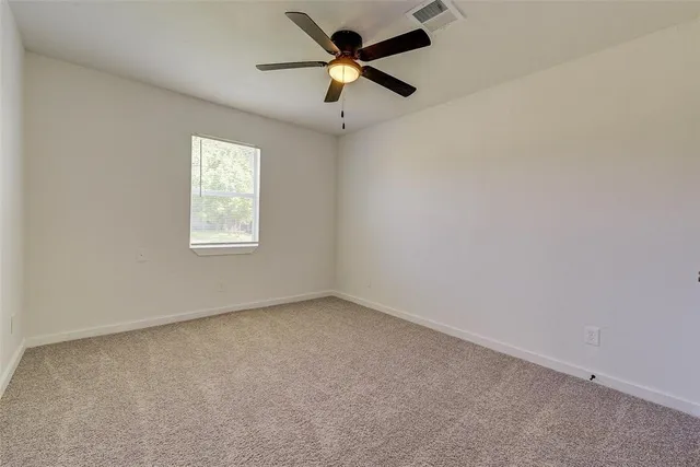 an empty room with a window and a fan
