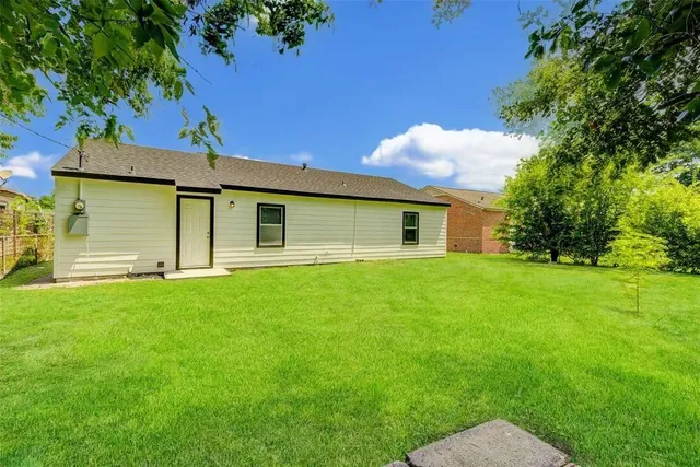 a backyard of a house with plants and large tree